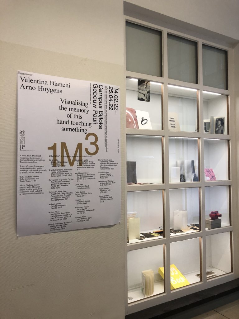 A vitrine with books is on the right and a poster with the writing 1m3 is on the left